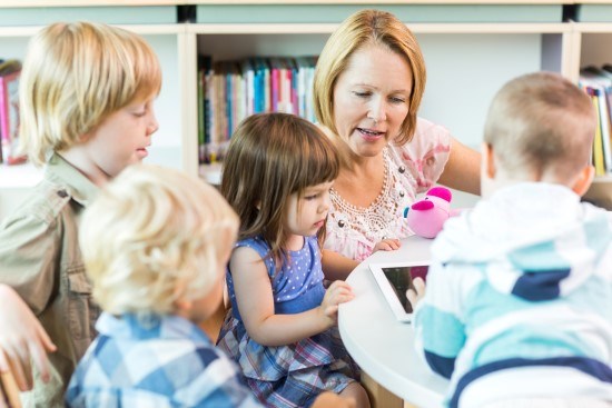 Barn som sitter runt ett bord med sin förskolepedagog.