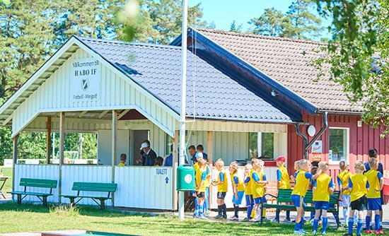 Barn i idrottskläder som står samlade på Slättens idrottsplats.
