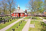 Röd träkyrka och en kyrkogård runtom.