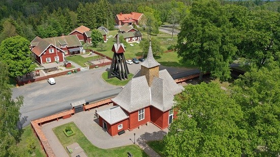 Brandstorps kyrka, röd kyrkobyggnad och röd klockstapel med omkrringliggande röd trähusbebyggelse