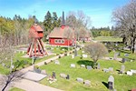 Rött kapell i trä med en kyrkogård runt.